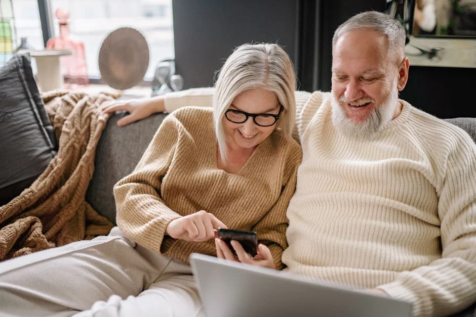 Couple de propriétaires comparant des installateurs solaires sur smartphone et ordinateur